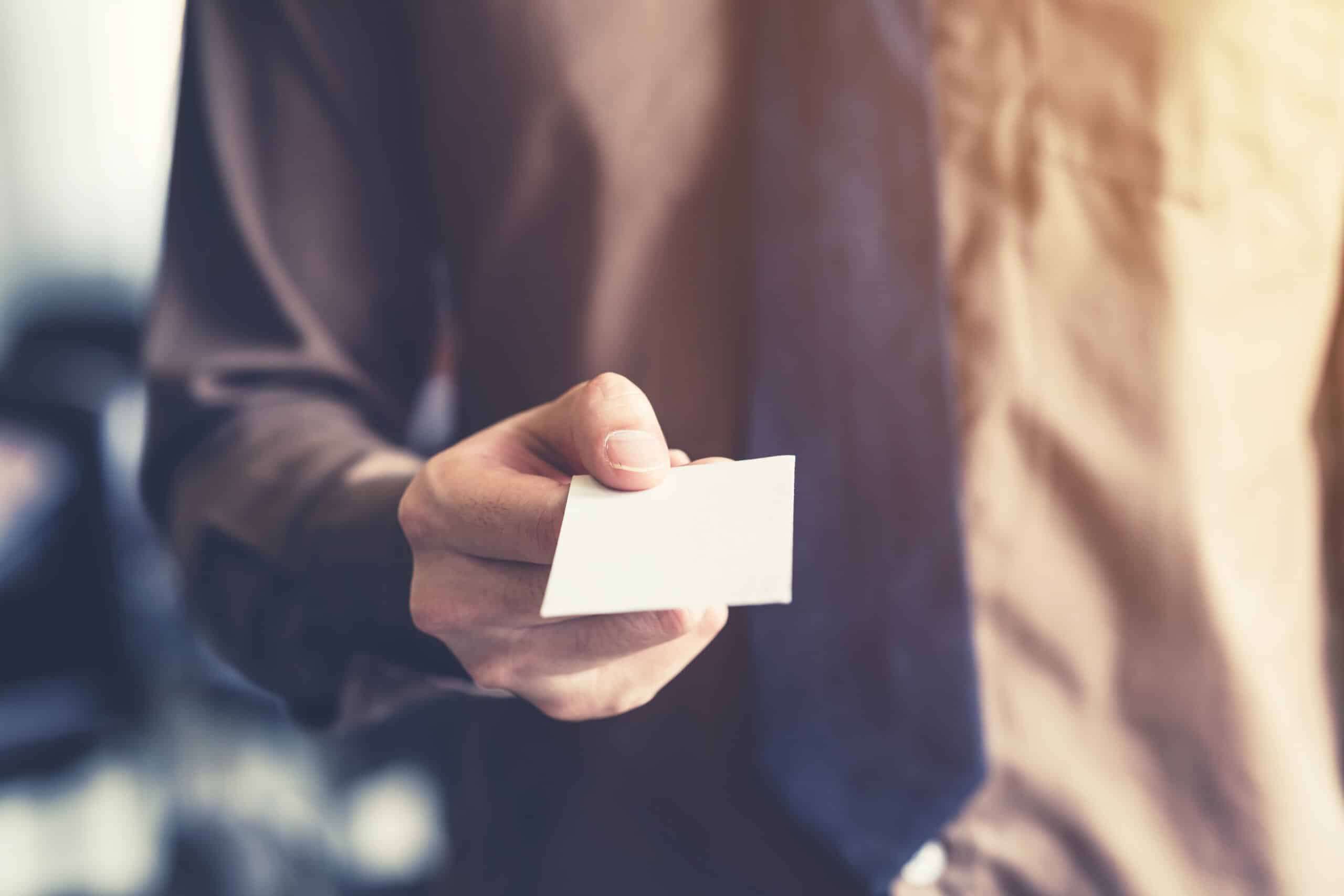 Business man holding white business card in the office. Vintage toned.