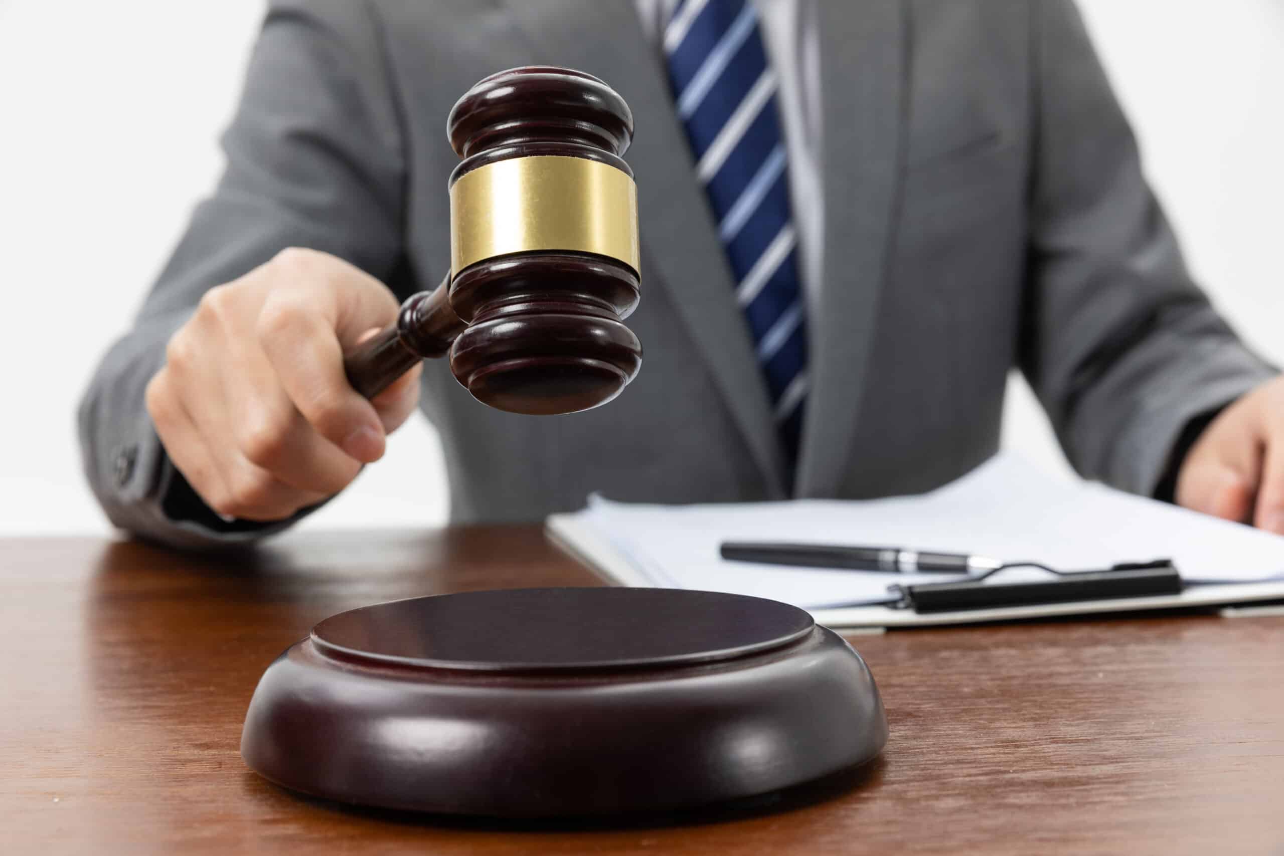 A closeup shot of a person holding a gavel on the table